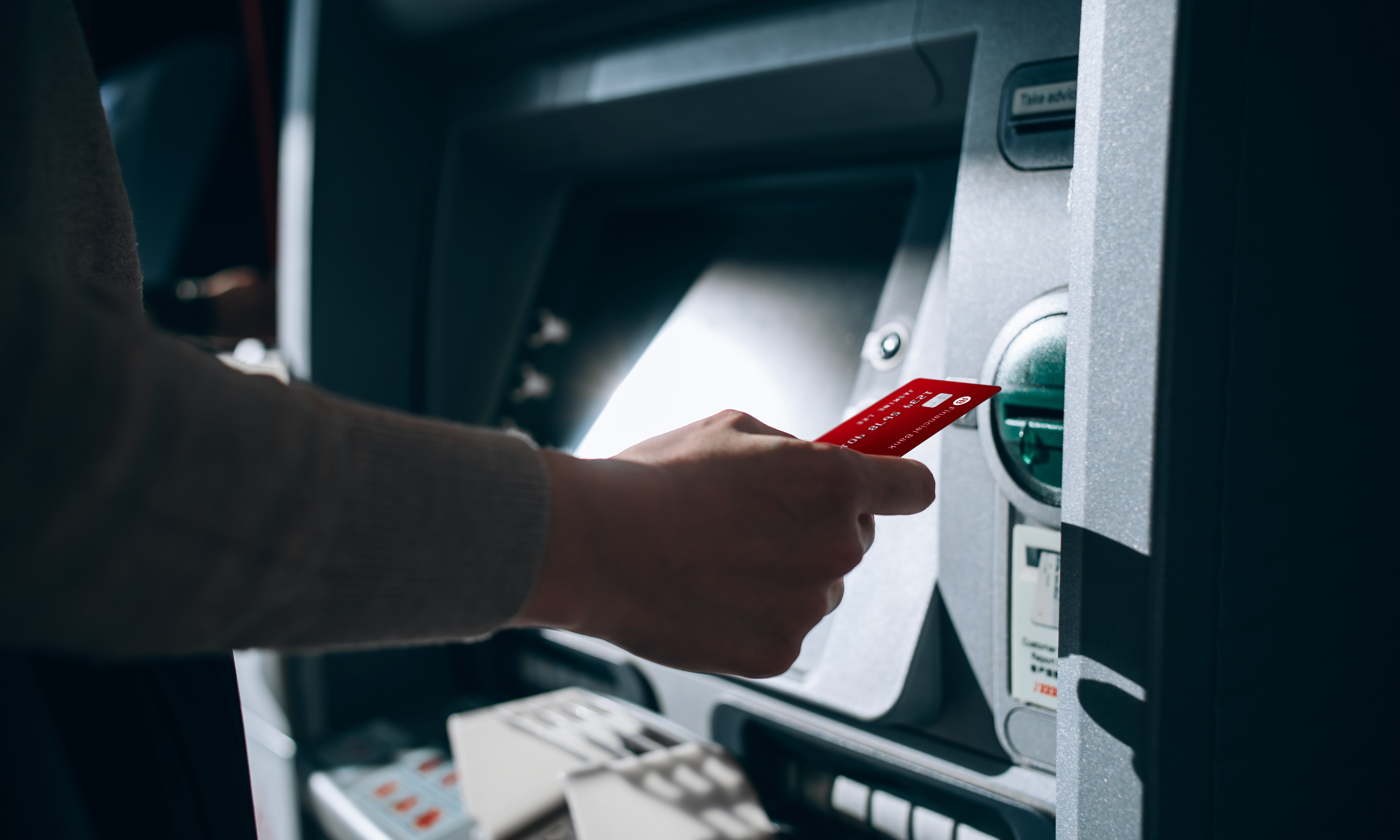 Close up of young woman inserting her bank card into automatic cash machine in the city. Withdrawing money, paying bills, checking account balances, transferring money. Privacy protection, internet and mobile security concept